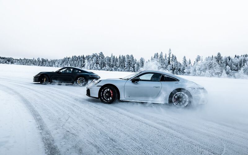 Dwa Porsche 911 w poślizgu obok siebie na śniegu