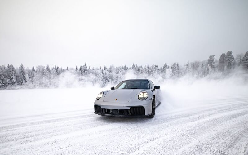 Srebrne Porsche 911 wyłania się z tumanu śniegu