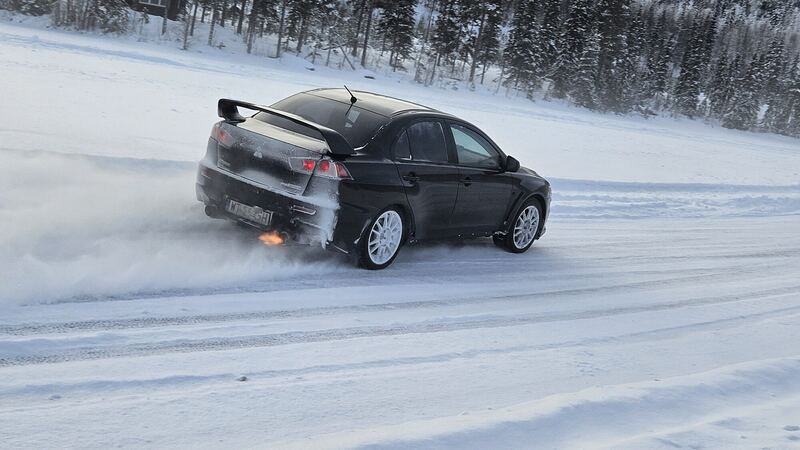 Czarne Mitsubishi Lancer Evo w poślizgu, za nim tuman śniegu