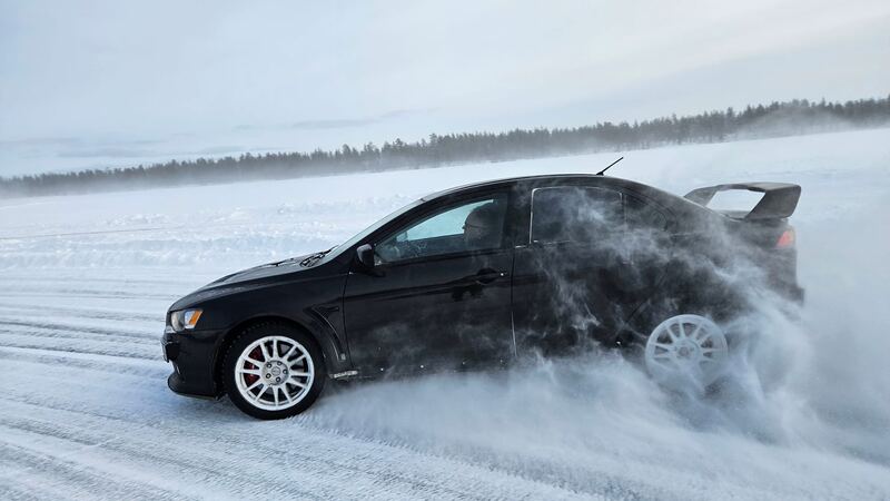 Czarne Mitsubishi Lancer Evo w poślizgu na lodzie