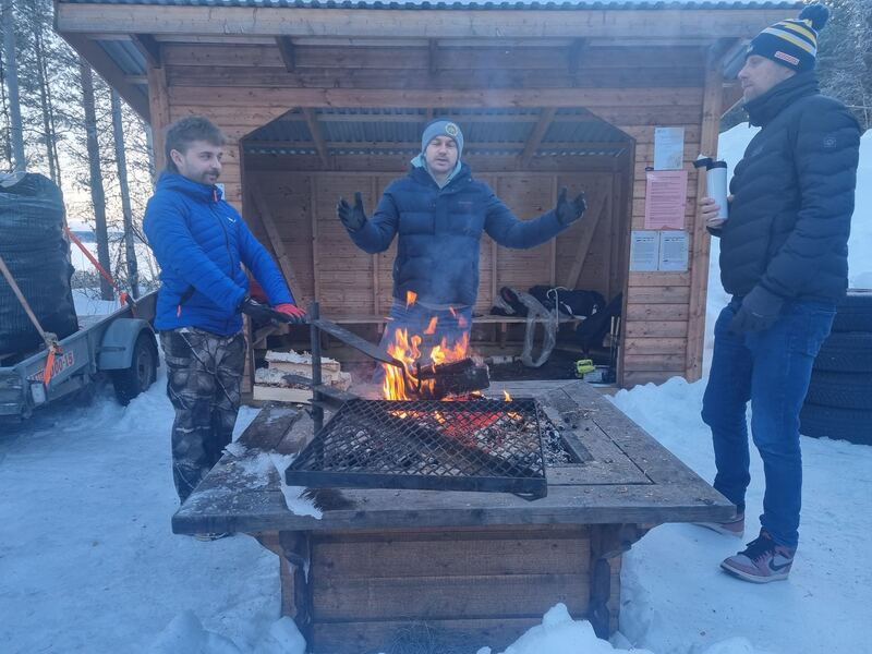 Uczestnicy przy ognisku w drewnianej wiacie, grill nad żarem