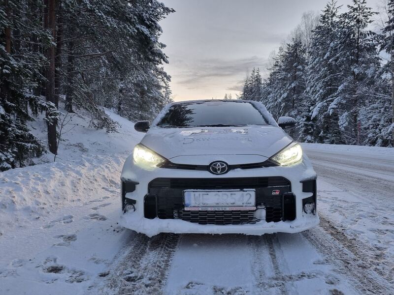 Biała Toyota GR Yaris na zaśnieżonej leśnej drodze
