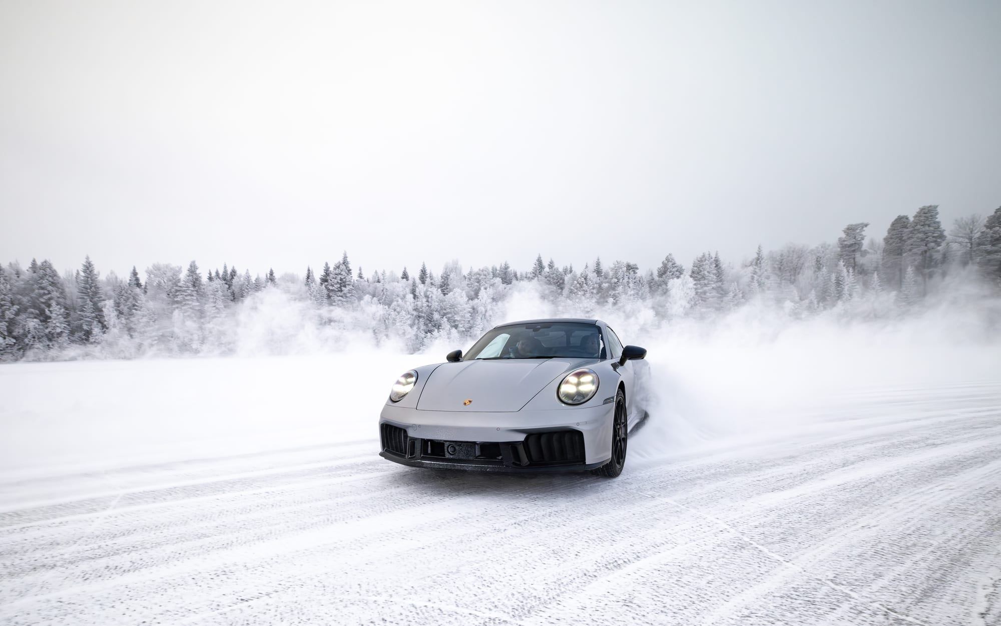 Srebrne Porsche 911 wyłania się z tumanu śniegu