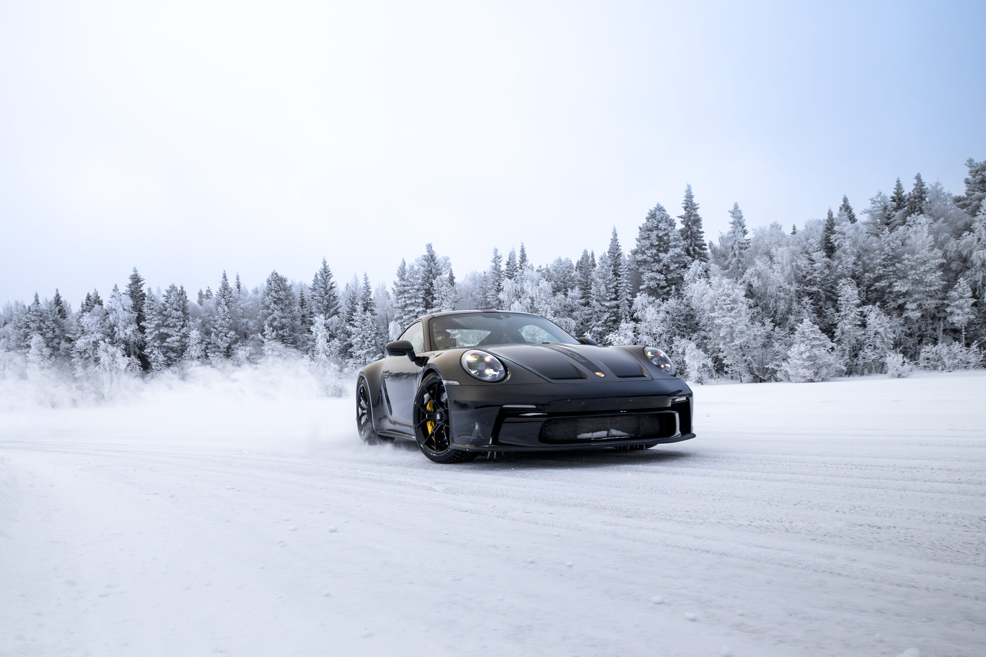Czarne Porsche 911 na lodzie pośród oszronionych drzew